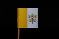 A official, original and national flag of Vatican City on toothpick on black background. A vertical bicolour of gold and white