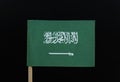 A official and unique flag of the Kingdom of Saudi Arabia on toothpick on black background. A green field with the Shahada or