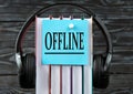 OFFLINE - word on a blue piece of paper on the background of a stack of books and headphones. Freedom of Information Act concept