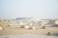 Offroad car in desert landscape white desert egypt. Low point of view. Car tracks in the sand and volcano hills in the background. Royalty Free Stock Photo