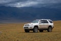 Offroad suv car on moutain plateau with mountains and rain clouds background. Summer vacation, travel concept. Royalty Free Stock Photo