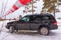 Offroad SUV `Jeep Grand Cherokee` 4x4 black color rides in winter on snow in the forest among pines and striped tape