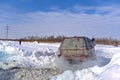 Offroad SUV `Range Rover 4x4` leaves on a bad snowy road in winter with a man leaning out of the window, raising a Blizzard