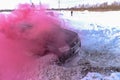 Offroad SUV `Suzuki Grand Vitara` 4x4 is rapidly actively driving on a broken road in clouds of colored crimson smoke