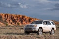 Offroad suv truck wtih red sandstone formations on background. Extreme wild journey concept. Sandstone rock. Outdoor landscape.