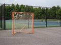 Offseason, beat up, rusted, ragged lacrosse goal sitting on asphalt court with nets tearing