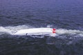 An offshore boat upside down and pulled by a vessel in the sea