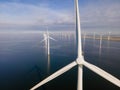 Offshore windmill park with clouds and a blue sky, windmill park in the ocean drone aerial view with wind turbine