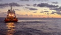Offshore workboat moves toward Derrick barge and other vessels on Bass Strait Australia at sunset.