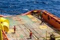 Offshore workers or riggers assisting placement of anchor buoy on deck of an anchor handling tug boat