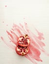 Oh so juicy. Studio shot of a halved pomegranate on a wooden surface covered with the juice of the fruit.