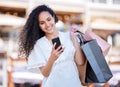 Oh look, another sale. a young woman using a smartphone while shopping against an urban background.