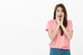 Oh my god, it is terrible. Portrait of shocked stunned cute brunette in pink t-shirt, dropping jaw and gasping, holding
