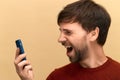 Oh no. Photo of young man with beard screaming in anger and shock, using mobile phone, feeling frustrated about information on Royalty Free Stock Photo