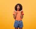 Oh no what happened. Worried african american sister with curly hair in trendy striped t-shirt and denim shorts gasping Royalty Free Stock Photo