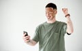 Oh yeah, I won. Studio shot of a young man with vitiligo cheering while using a cellphone against a white background. Royalty Free Stock Photo