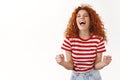 Oh yes. Lucky attractive fashionable redhead curly female yelling positive emotions scream yeah closed eyes achieve goal