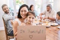 Ohana means family and family means nobody gets left behind. a little girl holding a sign while having lunch at home.