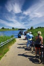 Path with waiting cyclists for small bicycle passenger ferry boat over Maas river to belgian border town Ophoven on the other side