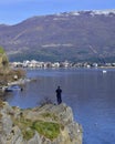 9OHRID, MACEDONIA - FEBRUARY 23, 2020: Man on the cliff picturing Lake Ohrid and city of Ohrid with smartphone in Ohrid