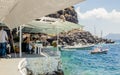 Oia, Santorini/ Greece 14JUL2019-Ammoudy Bay with fishing boats and fish tavernas. Tourists spend time and eat in traditional Gree