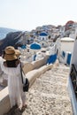 Female tourist with white dress viewing the Greek village with blue dome church, Oia, Santorini, Greece Royalty Free Stock Photo