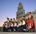 Traditional dance troop in costume pose in front of church before evening performance.