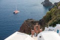 Yacht on the Aegean Sea and arch with bells, Oia, Santorini Island, Greece