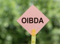 OIBDA Operating Income Before Depreciation And Amortization word written on pink road sign on a blurred green background