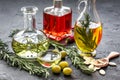 Oil in carafe with spices, olives and chili on stone background