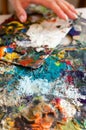 Oil color palette texture and female human hand close up, artist creative painting process. Messy abstract acrylic color Royalty Free Stock Photo