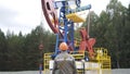 Oil field technical worker standing in front of crude oil pump unit. Engineer overseeing industrial oil pump jack. Oil Royalty Free Stock Photo