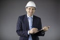 Oil engineer in hard hat makes notes on clipboard and looks at camera with smile Royalty Free Stock Photo