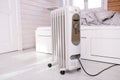 Oil-filled electrical mobile radiator heater for home heating and comfort control in the room in a wooden country house Royalty Free Stock Photo