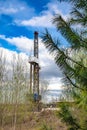 Oil and gas drilling rig in front of spring trees.