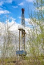 Oil and gas drilling rig in front of spring trees.