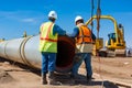 Oil and gas industry workers collaborating on a pipeline construction project, with heavy machinery and equipment on site Royalty Free Stock Photo