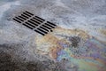 An oil or gasoline slick against the backdrop of an asphalt road flows into a storm drain. Environmental problems of Royalty Free Stock Photo