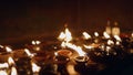 Oil lamps flicker in serene Buddhist temple, flame glow in dark, symbolize peace, faith. Devotees light votives