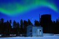 Oil lease with a bitumen tank illuminated by the northern lights