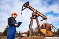 Oil man checking work of oil well pump jack. Royalty Free Stock Photo