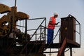 Oil man controlling work of petroleum pump jack. Royalty Free Stock Photo