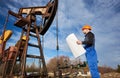 Oil man controlling work of pump jack. Royalty Free Stock Photo