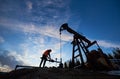 Oil man working in oil field with pump jack.