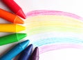 Oil pastel crayons lying on a paper with painted rainbow Royalty Free Stock Photo