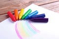 Oil pastel crayons lying on a paper with painted rainbow Royalty Free Stock Photo