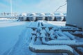 White tanks in tank farm with iron staircase in snow