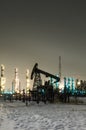 Oil pump and wellhead at the background of refinery by night