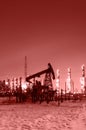 Oil pump and wellhead at the background of refinery by night