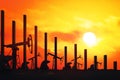 Oil pumps silhouetts with falling graphic chart, sunset in the background. Oil price fall concept, 3d rendering